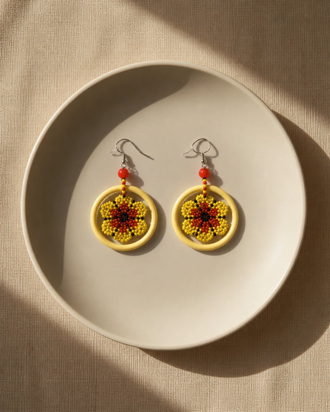 Golden Sun floral hoop earrings on an ivory ceramic dish